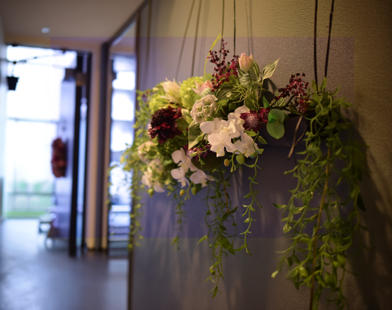 マンションの玄関の廊下の壁に飾られたアーティフィシャルフラワーによるインテリアフラワー